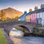 The image is well-composed, incorporating a bridge, river, colorful buildings, and a mountain backdrop. The lighting is excellent, creating a warm and inviting atmosphere. The image is sharp and the key elements, such as the bridge and buildings, are in focus. The colors are accurate and vibrant, and the image has a photo-realistic quality. Overall, the image is visually appealing and meets the criteria well. The composition is strong, the lighting is well-managed, and the image is sharp and color-accurate. The focus is well-placed on the bridge and buildings. The photo-realistic quality is also a plus.