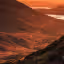 This image showcases a stunning landscape with mountains, a winding path, and an eagle in flight. The lighting is warm and golden, suggesting it was taken during sunset or sunrise. The composition is well-balanced, with the path leading the eye through the scene. The eagle is a key element and is reasonably in focus. The image is sharp and appears photo-realistic. The color accuracy is good, although the overall tone is warm due to the lighting conditions. The image is well-lit and well-composed. The key elements are in focus. The image is sharp and appears photo-realistic. The image is visually appealing and does not contain any unwanted elements.