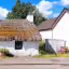 The image shows a charming cottage with a thatched roof. The composition is decent, although slightly off-center. The lighting is good, with bright daylight and clear skies. The sharpness is acceptable, but could be improved. The colors appear accurate. The image is reasonably photo-realistic. The key elements, such as the cottage and roof, are in focus. Overall, the image is well-executed and visually appealing. The presence of signage and the plant pot are acceptable elements. The composition could be improved to better highlight the cottage. The image is well-lit and color accurate. Sharpness is good, but could be better to capture finer details of the thatched roof. The image is photo-realistic.