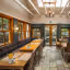 An empty dining room or restaurant interior with wooden tables and chairs, natural light from skylights and windows, and decorative lighting.