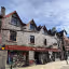 The image shows the exterior of a shop called 'The Granite House'. The composition is decent, capturing the building and its surroundings. The lighting is good, with natural light illuminating the scene. The image is reasonably sharp, although it could be sharper. The colors appear accurate. The image is photo-realistic. The key elements, such as the shop front and the building's facade, are in focus. The presence of a bicycle parked in front of the shop is slightly distracting but not detrimental. Overall, the image is well-presented and informative.
